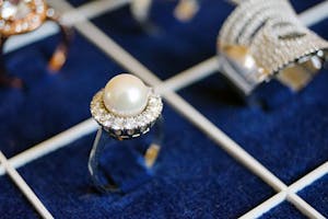 Close-up of a pearl ring with diamonds on a luxurious display.